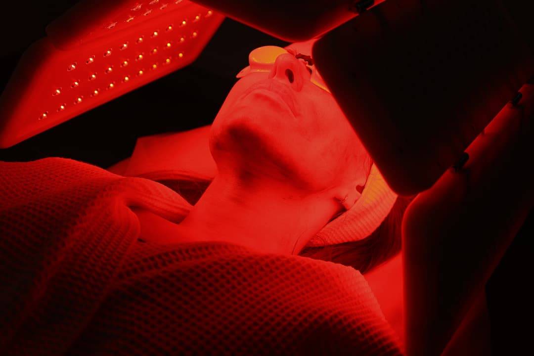 Led Skin Therapy - woman laid down underneath a red LED light panel with goggles protecting her eyes